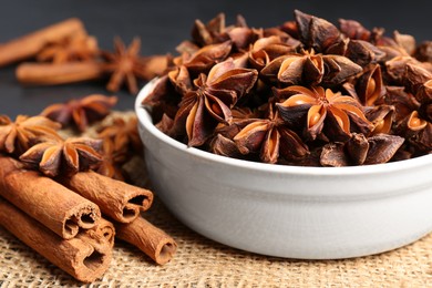 Photo of Bowl with aromatic anise stars and cinnamon sticks on table, closeup