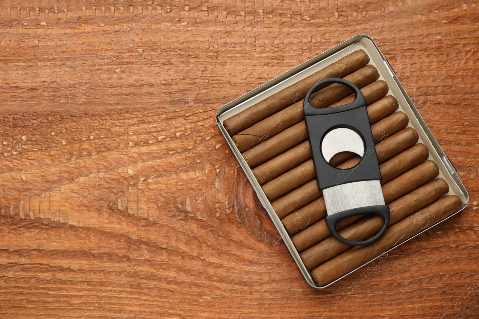 Photo of Cigars and guillotine cutter on wooden table, top view. Space for text