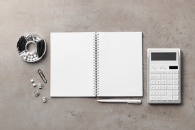 Ballpoint pen, notebook and calculator on gray table, flat lay