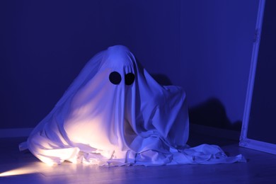 Photo of Creepy ghost. Woman covered with sheet in blue light