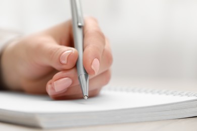 Photo of Woman writing with pen in notebook, closeup