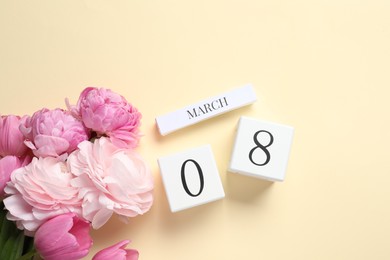 International Women's day - 8th of March. Wooden block calendar and beautiful flowers on beige background, flat lay