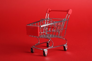 Small metal shopping cart on red background