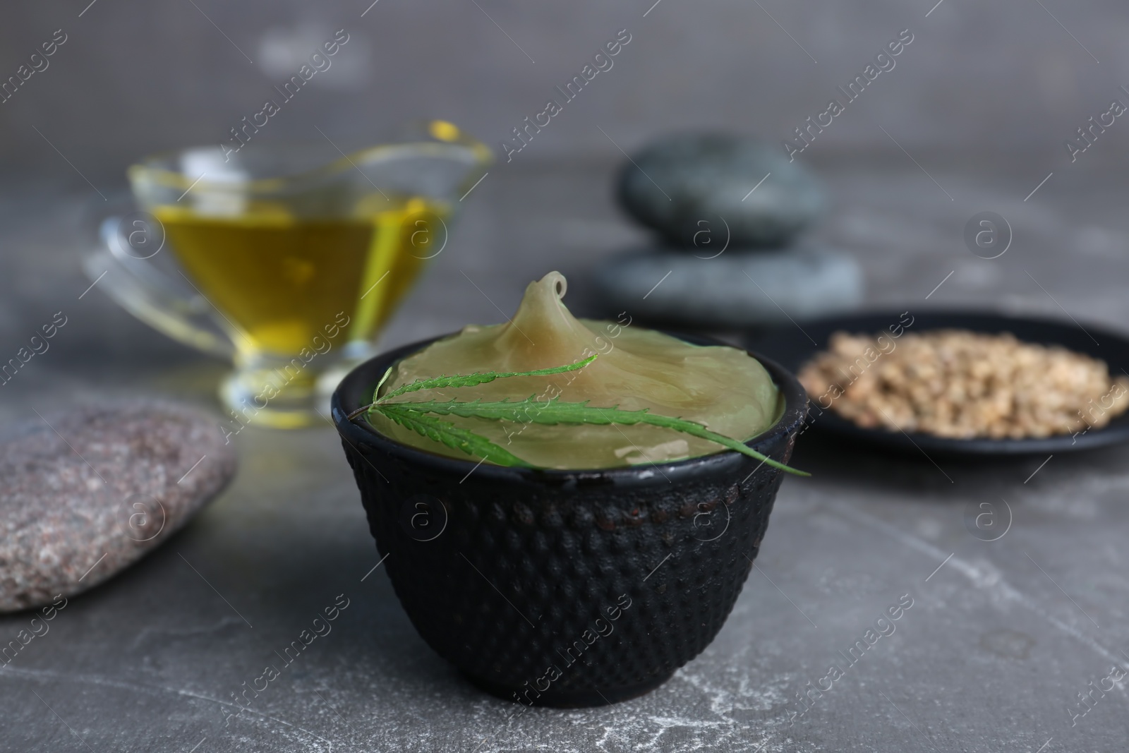 Photo of Bowl with hemp lotion on grey table