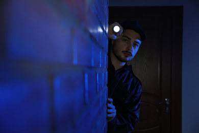 Male security guard with flashlight in dark corridor