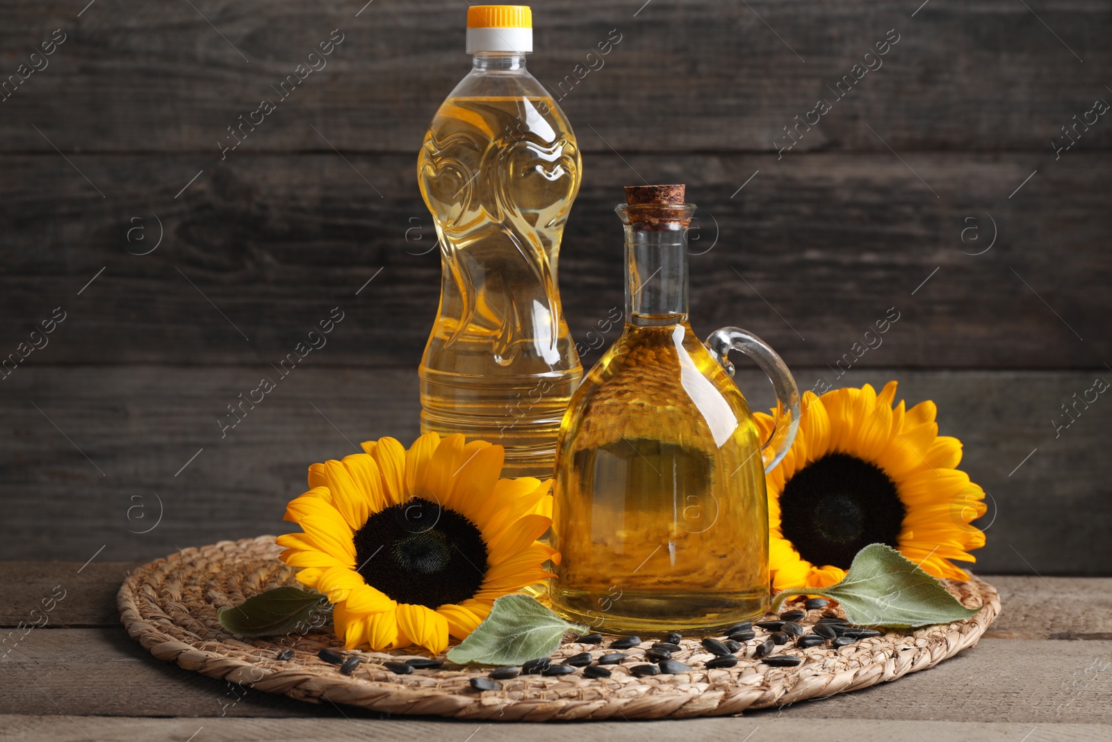 Photo of Sunflower cooking oil, seeds and yellow flowers on wooden table