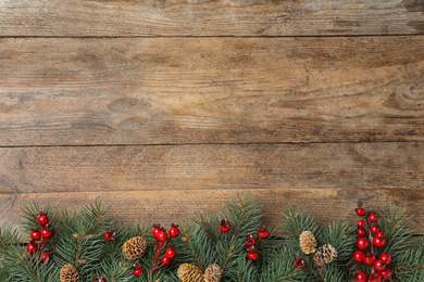 Photo of Flat lay composition with fir branches and berries on wooden background, space for text. Winter holidays