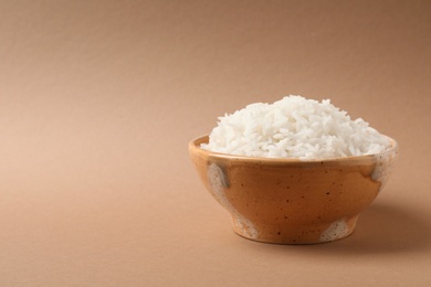 Photo of Bowl of tasty cooked rice on color background. Space for text