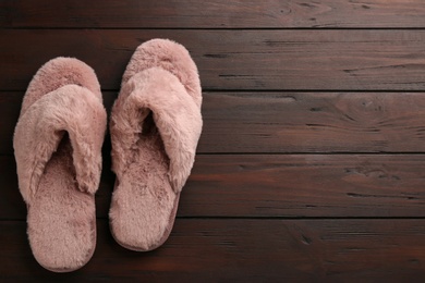 Pair of stylish soft slippers on wooden background, flat lay. Space for text