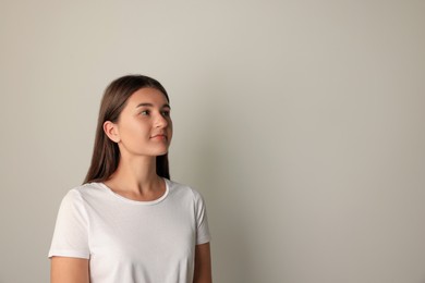 Photo of Beautiful young woman in white t-shirt on light background. Space for text