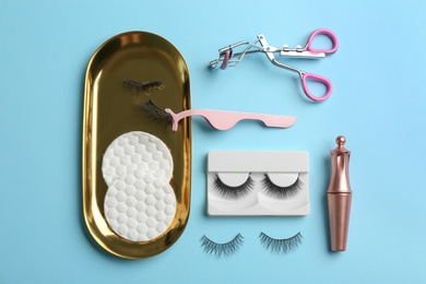Photo of Flat lay composition with magnetic eyelashes and accessories on light blue background