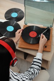 Woman listening to music with turntable at home, above view