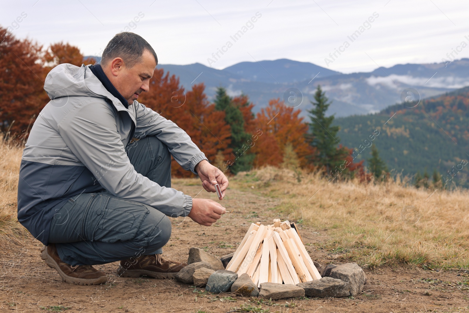 Photo of Man making bonfire in mountains. Camping season