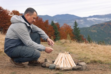 Photo of Man making bonfire in mountains. Camping season