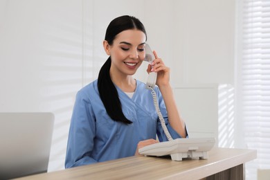 Photo of Receptionist talking on phone at countertop in hospital