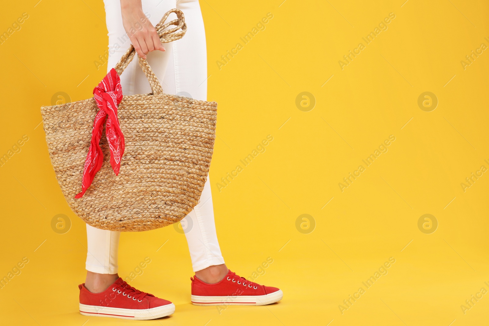 Photo of Young woman with stylish straw bag on yellow background, closeup. Space for text