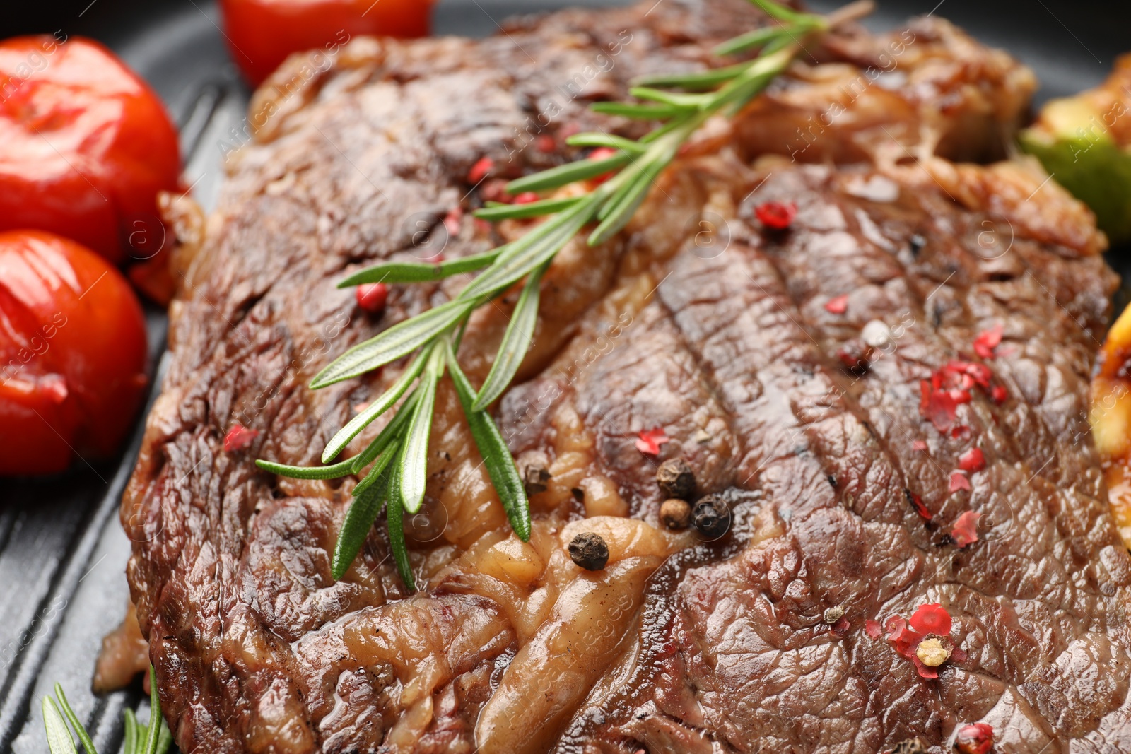 Photo of Delicious grilled beef steak, tomatoes and rosemary in frying pan, closeup