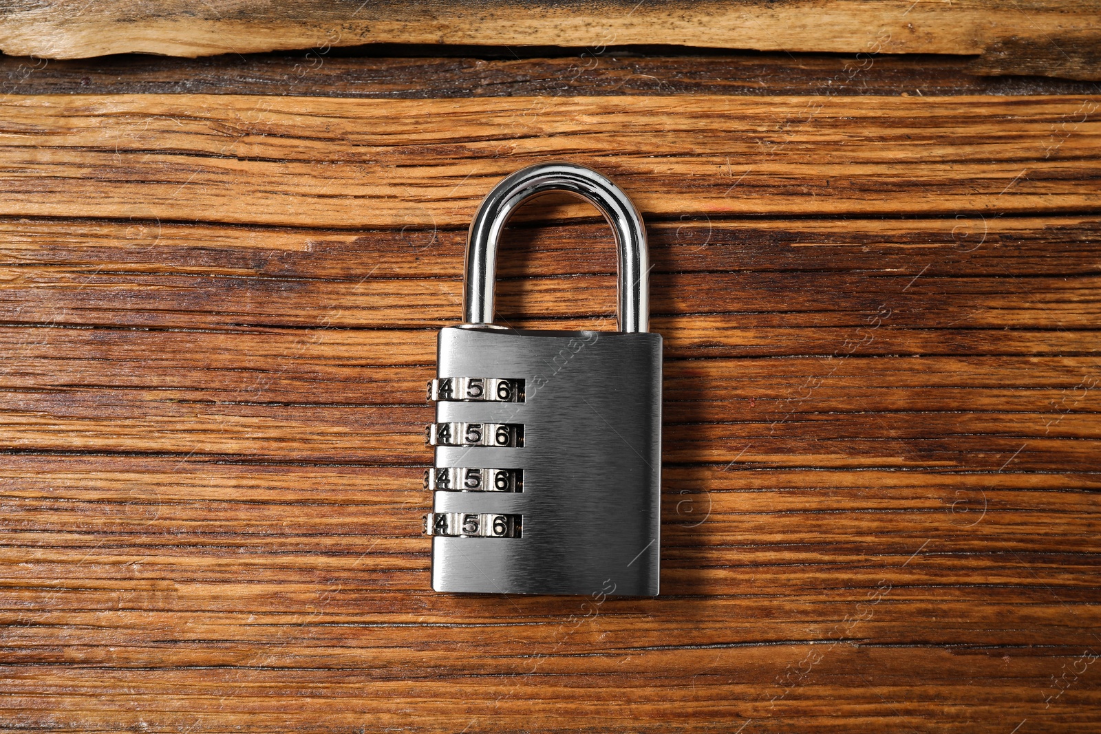 Photo of One steel combination padlock on wooden table, top view