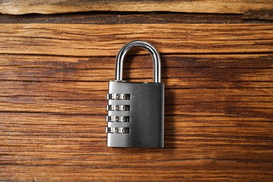 Photo of One steel combination padlock on wooden table, top view
