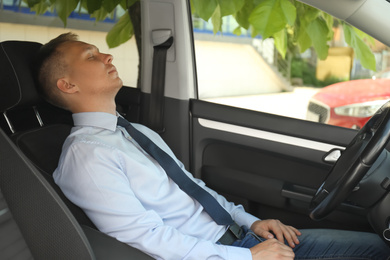 Tired young man sleeping in his modern car