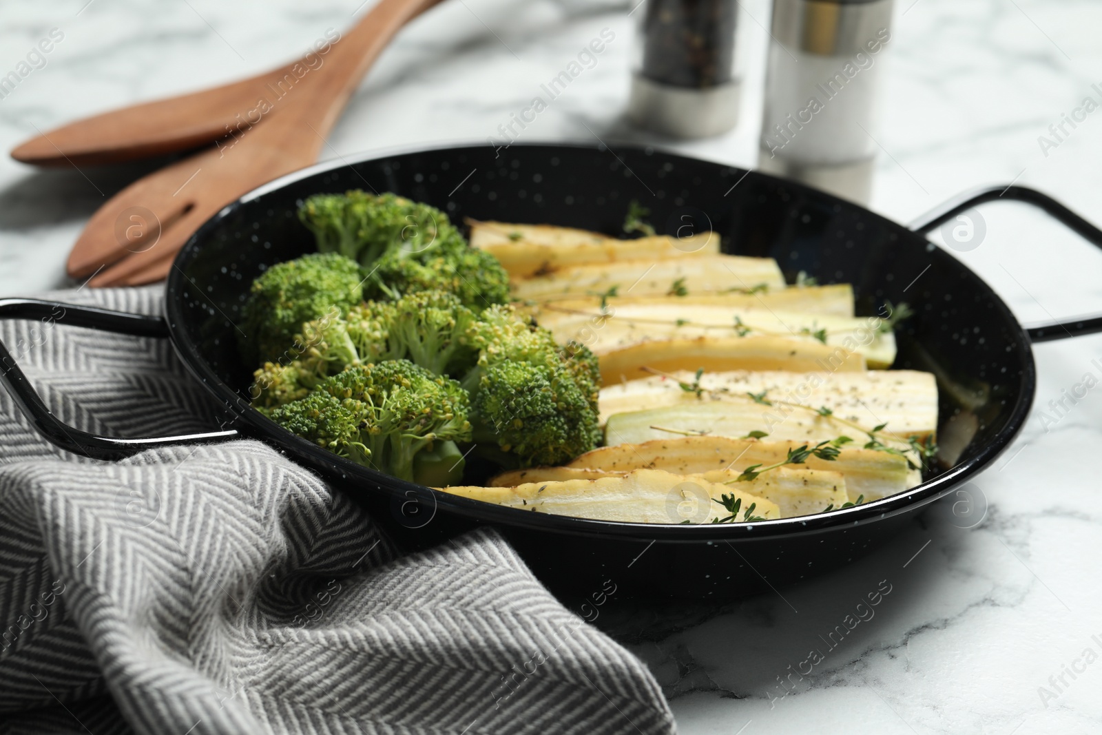 Photo of Raw white carrot and broccoli in frying pan on white marble table, closeup