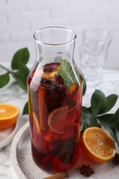 Photo of Delicious punch drink in bottle, spices and citrus fruits on white table