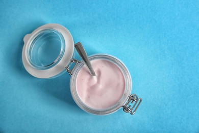 Jar with tasty yogurt on color background, top view