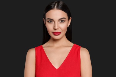 Portrait of young woman wearing beautiful red lipstick on black background
