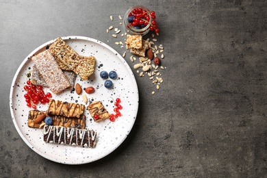 Photo of Plate with different grain cereal bars on table, top view. Healthy snack