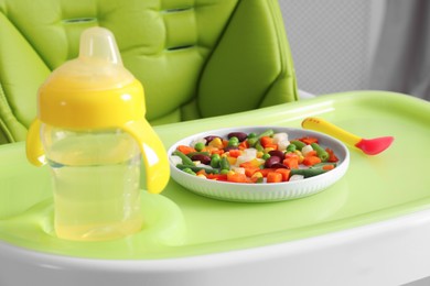 Photo of Baby high chair with healthy food and water, closeup view