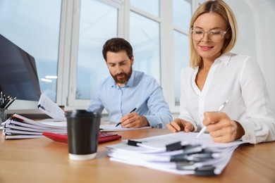 Photo of Happy businesspeople working with documents at wooden table in office