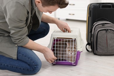 Photo of Travel with pet. Man closing carrier with cat indoors