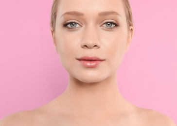 Photo of Portrait of young woman with beautiful face on pink background, closeup