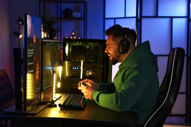 Photo of Man playing video games with controller at table indoors