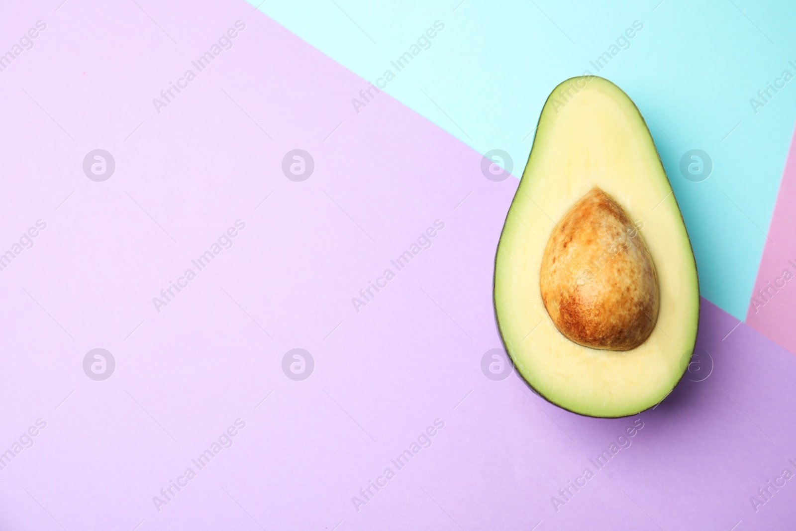 Photo of Cut fresh ripe avocado on color background, top view with space for text