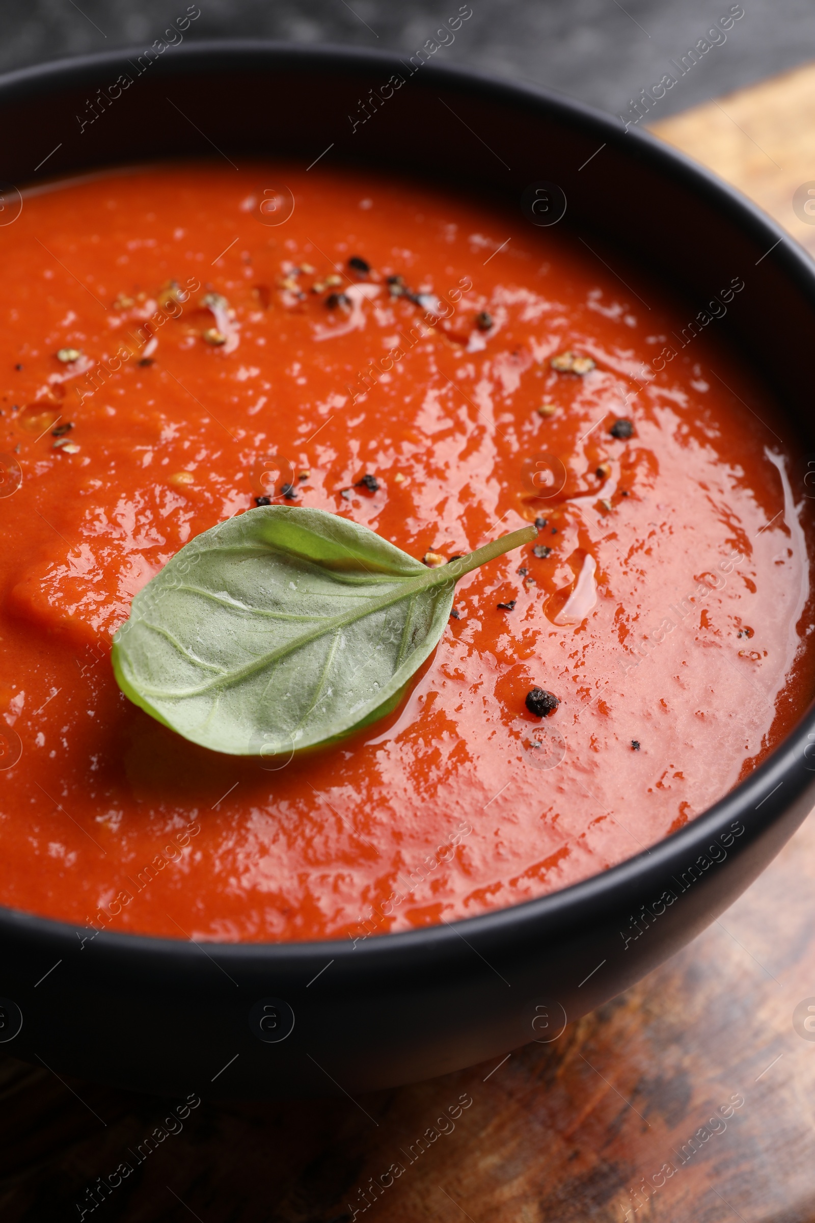 Photo of Delicious tomato cream soup in bowl on table, closeup