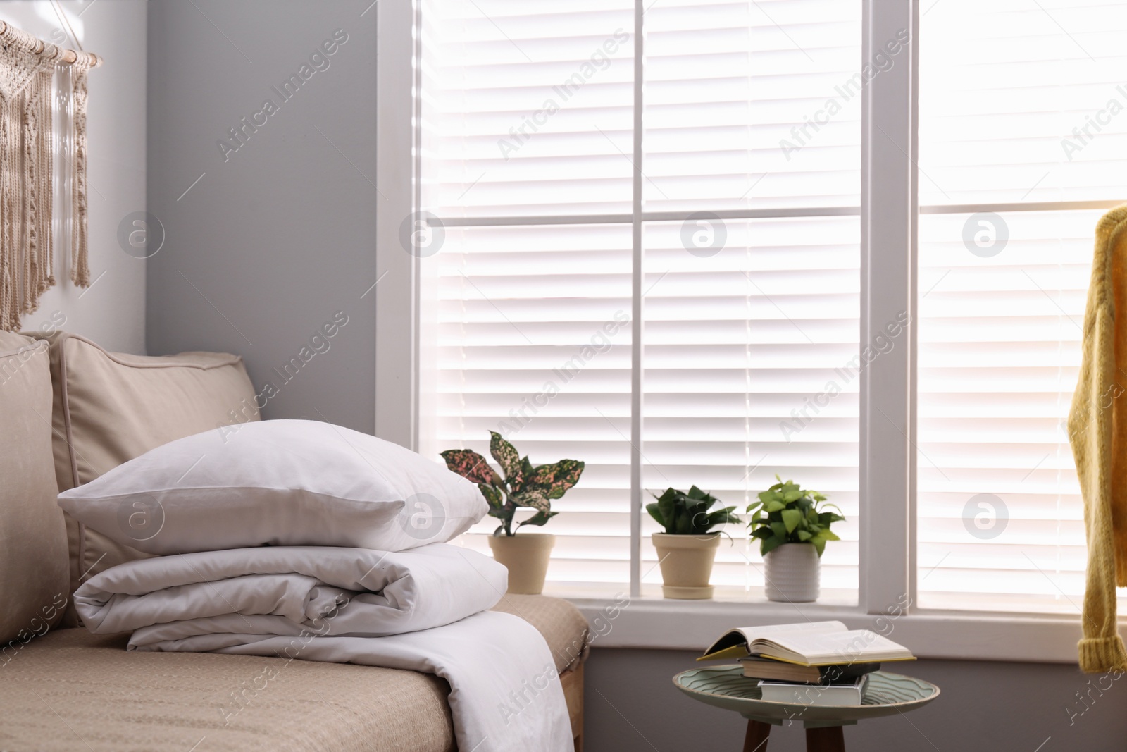 Photo of Comfortable sofa with blanket near window indoors