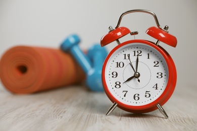 Alarm clock on floor indoors, space for text. Morning exercise