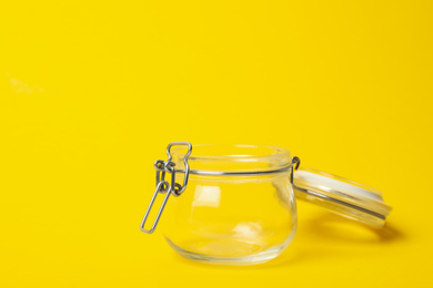 Open empty glass jar on yellow background