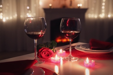Photo of Romantic table setting with wine, rose and candles for Valentine's day dinner indoors