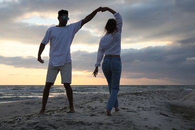 Photo of Happy couple dancing on beach at sunset