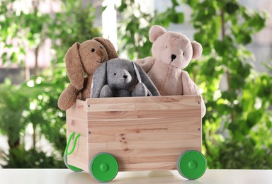 Wooden cart with stuffed toys on table against blurred background