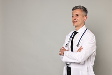 Photo of Happy doctor with stethoscope on grey background, space for text