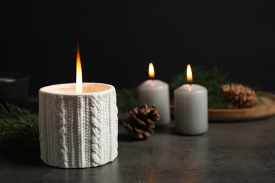 Candle and Christmas decor on dark grey table, space for text