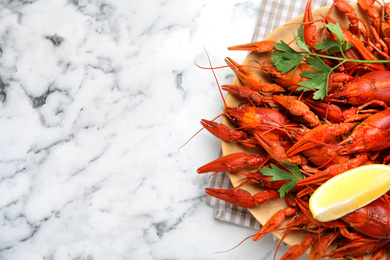 Photo of Delicious boiled crayfishes on white marble table, top view. Space for text