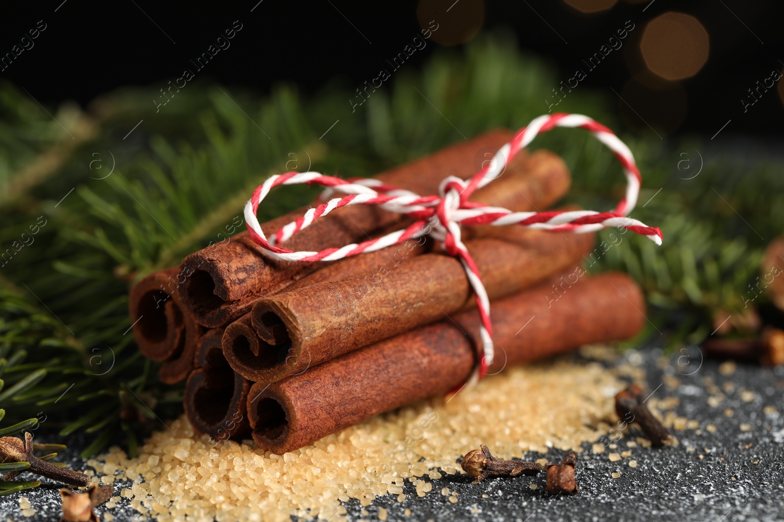 Photo of Different aromatic spices and fir branches on grey textured table, closeup