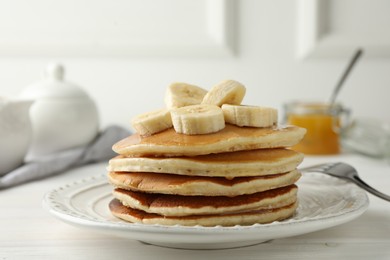 Photo of Delicious pancakes with bananas and honey on white wooden table, closeup