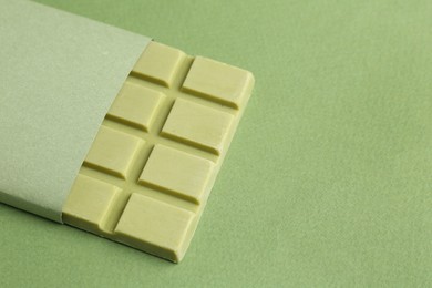 Tasty matcha chocolate bar on green background, closeup. Space for text