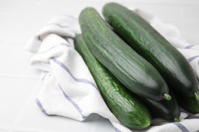 Photo of Fresh cucumbers and cloth on white table, closeup. Space for text