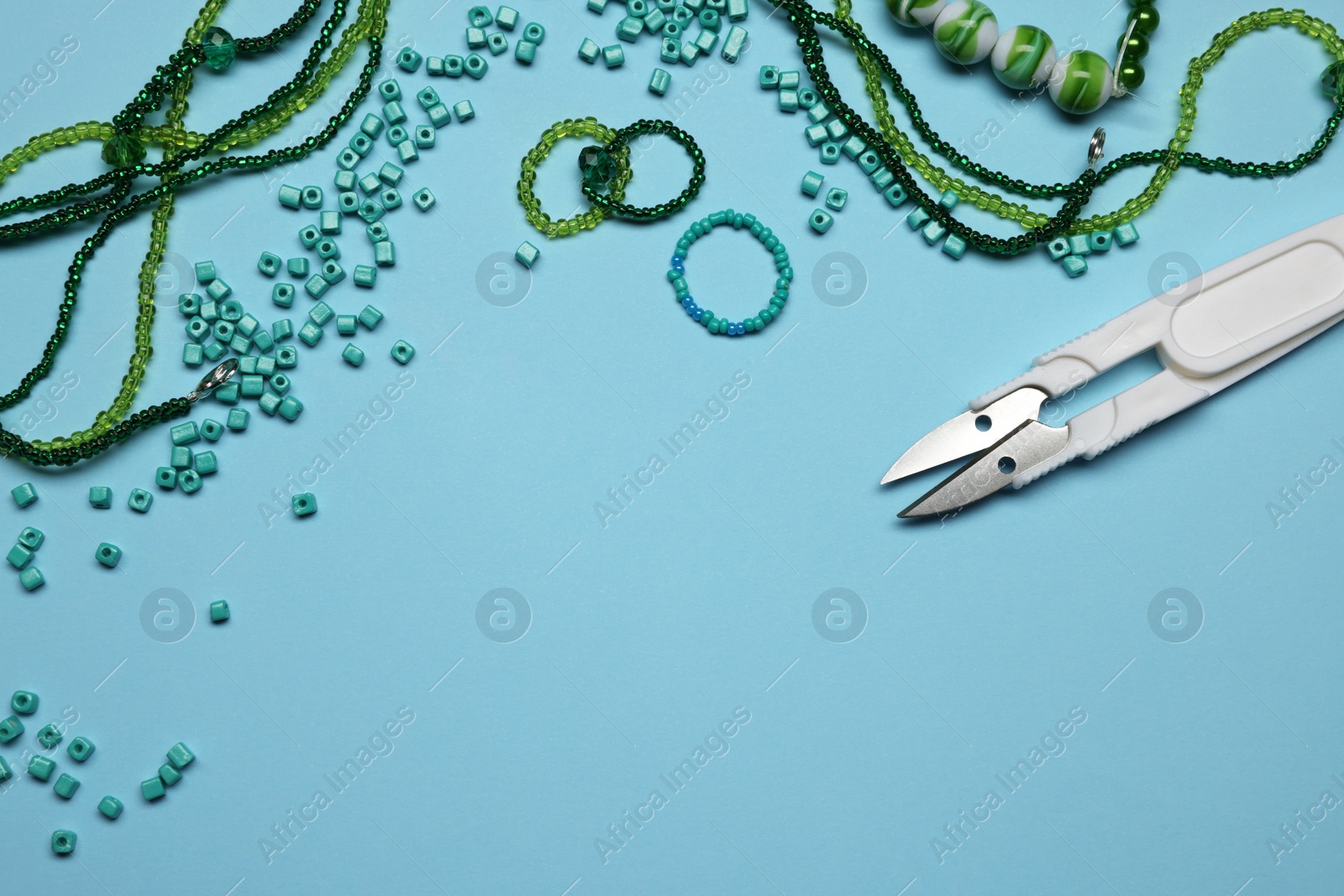 Photo of Flat lay composition with different colorful beads on light blue background, space for text